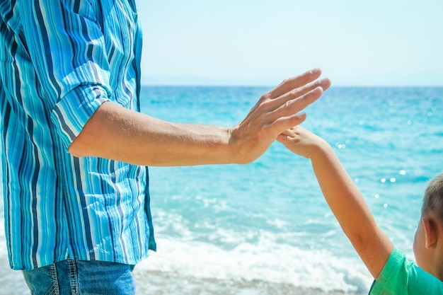 Mani di un genitore e di un bambino felici in riva al mare durante un viaggio nella natura