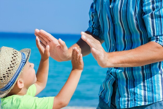 Mani di un genitore e di un bambino felici in riva al mare durante un viaggio nella natura