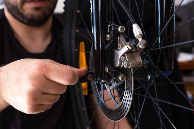 Mani di un meccanico che regola la ruota di una bicicletta