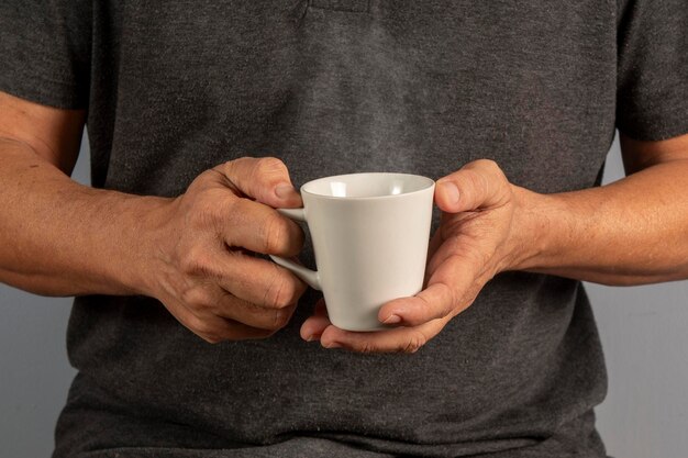 Mani di un uomo anziano che tiene una tazza con una bevanda calda