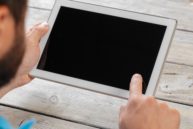 Mani di un uomo che tiene il dispositivo tablet su un tavolo di lavoro in legno