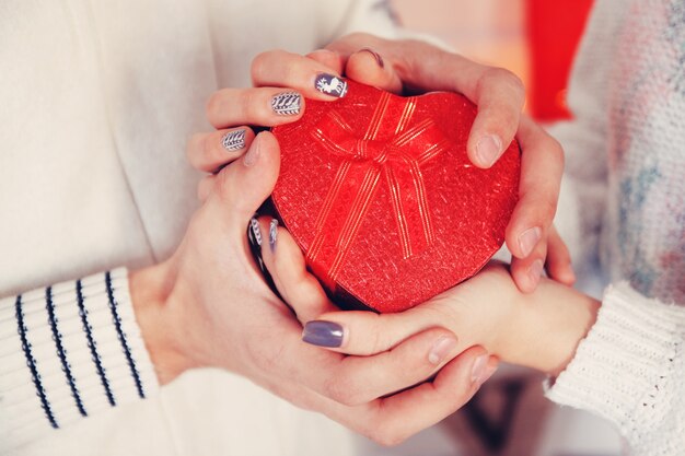 Mani di un uomo e di una donna che tengono una scatola a forma di cuore