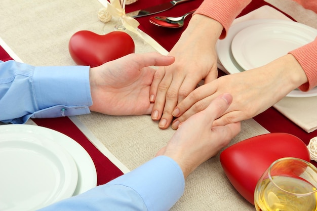 Mani di una coppia romantica sul tavolo di un ristorante