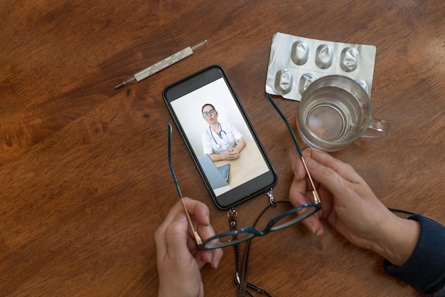 Mani di una donna anziana con uno smartphone Ritratto di un medico su uno schermo mobile Medicina online Un pensionato si consulta con uno psicologo tramite collegamento video