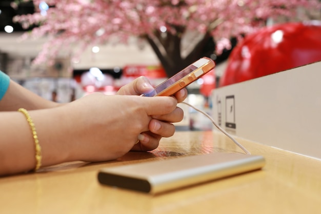 mani di una donna che gioca uno smartphone sul tavolo di legno.