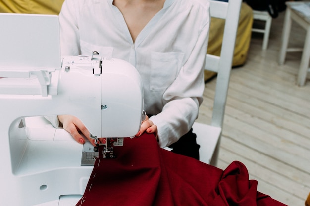 Mani di una donna che lavora su un primo piano della macchina da cucire. Concept sartoriale e design dell'abbigliamento.