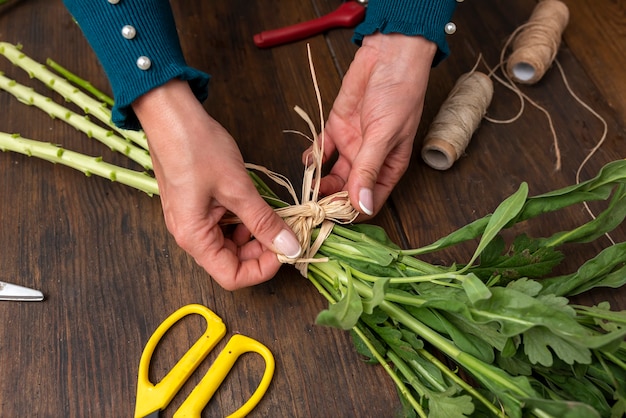 Mani di una donna che organizza un mazzo di fiori su un tavolo