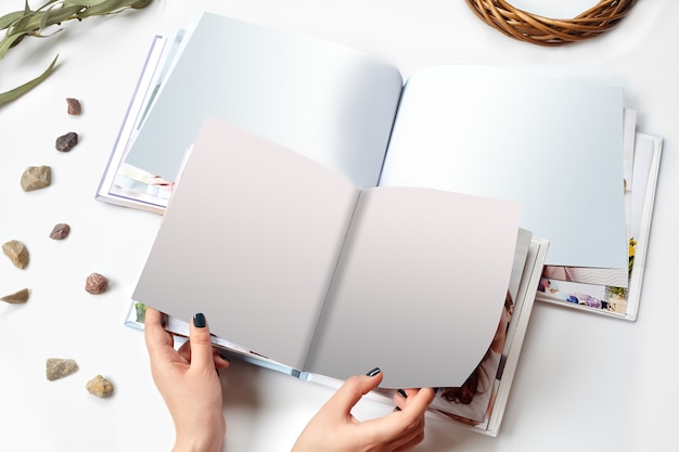 Mani di una donna che tiene due libri fotografici aperti con copertina rigida e pagina vuota