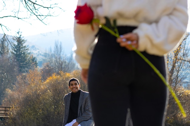 Mani di una donna innamorata che nasconde una rosa per il suo fidanzato Concetto di una rosa per il fidanzato