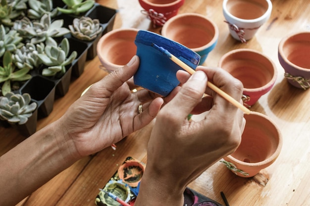 Mani di una donna mulatta latina che dipinge vasi di terracotta per piantare piante succulente