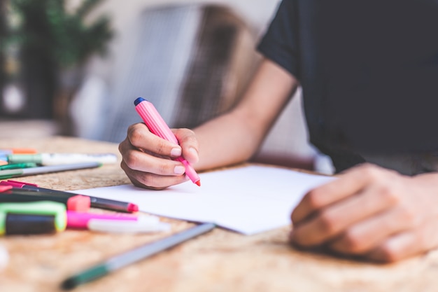 Mani di una giovane donna che scrive lettera e leggendo un libro