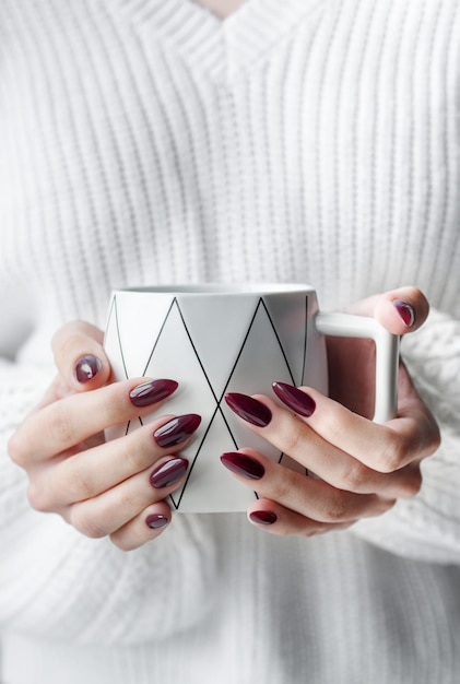 Mani di una giovane donna con il manicure bianco sulle unghie