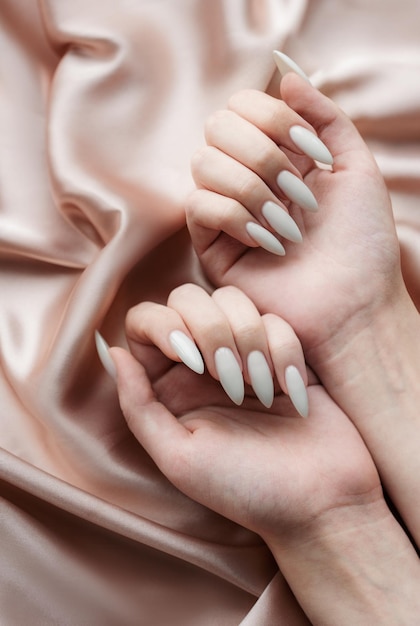 Mani di una giovane donna con il manicure bianco sulle unghie