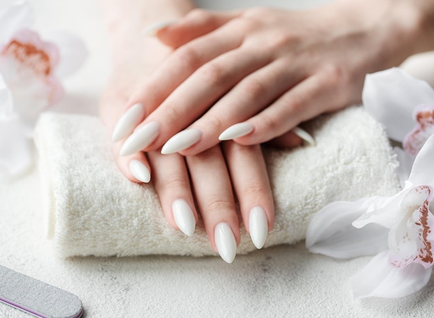 Mani di una giovane donna con il manicure bianco sulle unghie