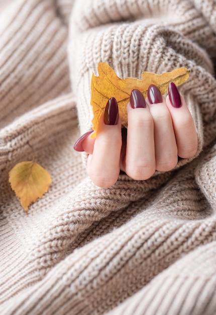 Mani di una giovane donna con manicure rosso scuro sulle unghie