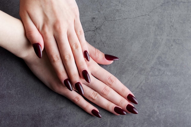 Mani di una giovane donna con manicure rosso scuro sulle unghie