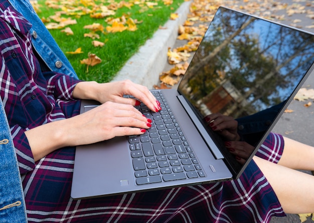 Mani di una giovane ragazza con un computer portatile nel parco