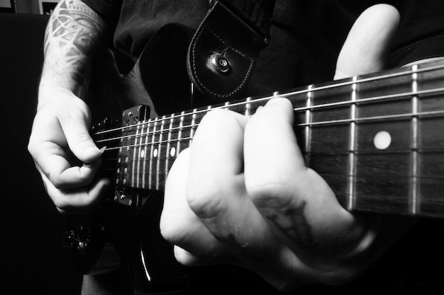 Mani di una persona che suona una chitarra in bianco e nero