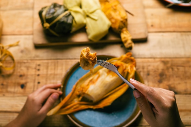 Mani di una persona che taglia un tamale con una forchetta Tamale tipico cibo messicano