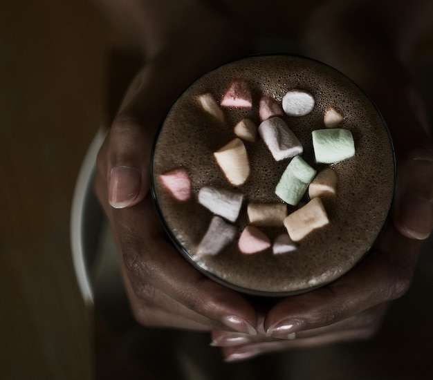 Mani di una ragazza africana che tiene il cacao con un marshmallow