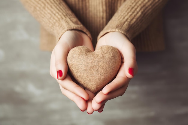 Mani di una ragazza con un cuore su sfondo grigio