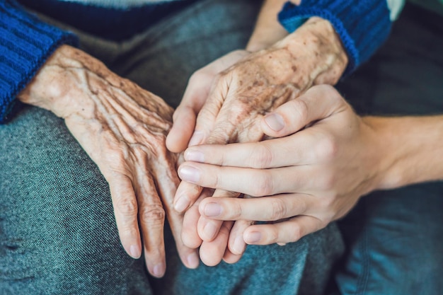 Mani di una vecchia e di un giovane. La cura degli anziani. avvicinamento