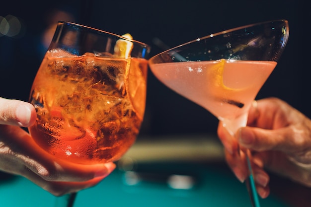 Mani di uomo e donna tifo con bicchieri di champagne rosa.