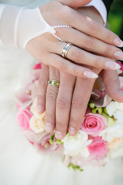 Mani e anelli sul bouquet da sposa