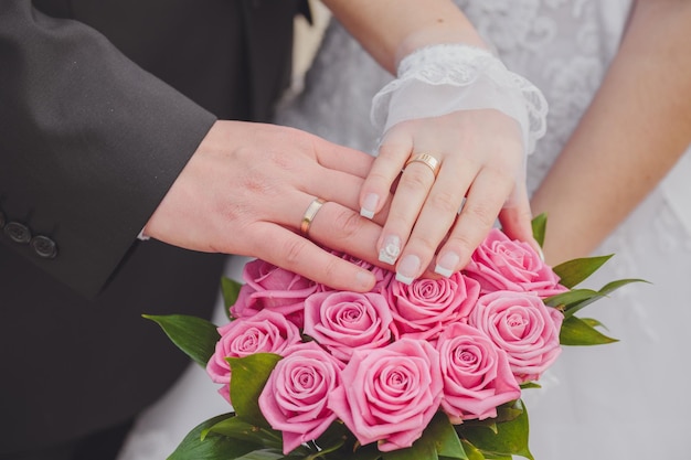 Mani e anelli sul bouquet da sposa