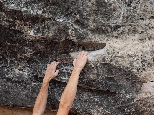 Mani e dita fasciate con magnesia bianca di un giovane scalatore in un ambiente naturale. Concetto di bouldering.