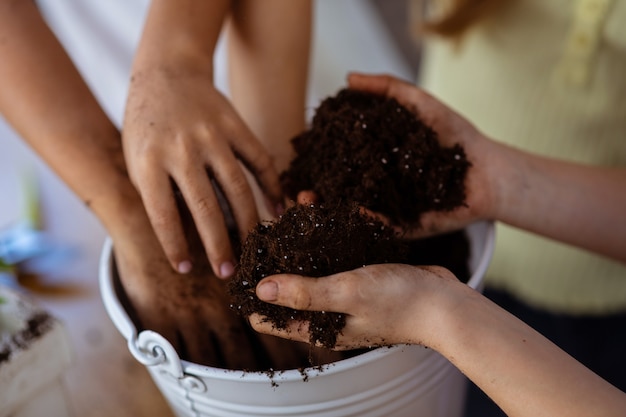 Mani e terra. Primo piano di bambini e insegnanti che tengono il terriccio alla lezione di ecologia a scuola