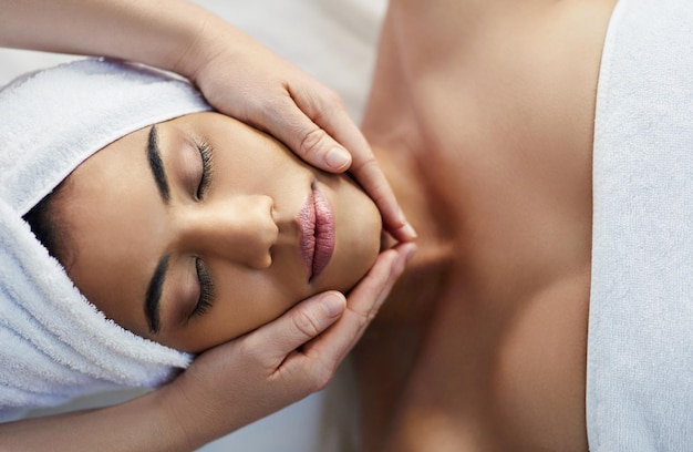 Mani e viso della donna in relax per massaggi cura della pelle o trattamenti di bellezza spa sul letto sopra al resort Vista dall'alto della donna che si rilassa con gli occhi chiusi per una terapia calma benessere sano o viso cosmetico