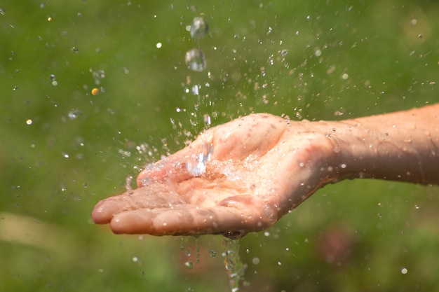 Mani femminili bagnate e schizzi d'acqua limpida