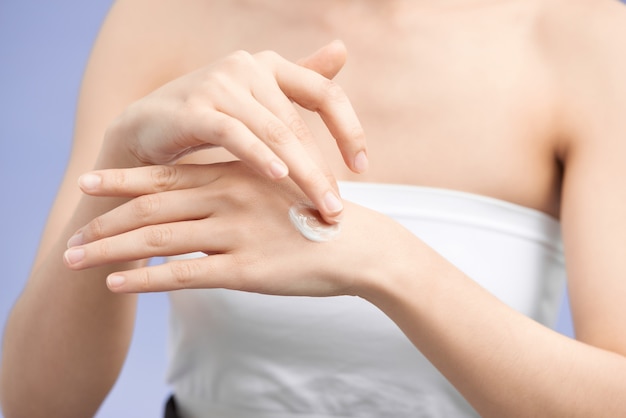 Mani femminili che applicano crema per le mani