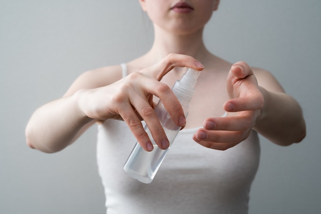 Mani femminili che applicano fine antibatterica del sapone liquido su