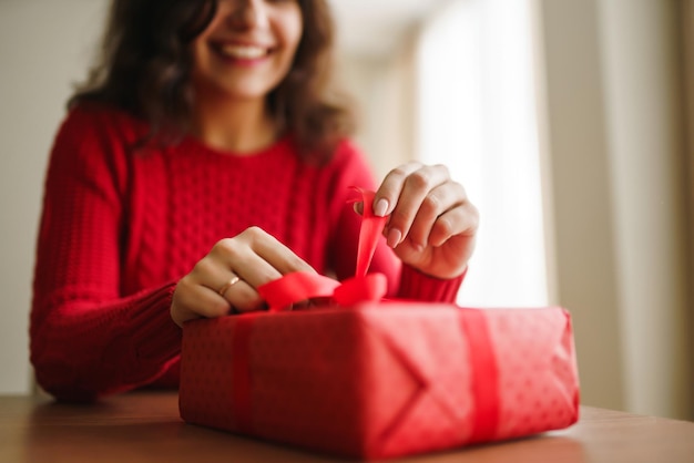 Mani femminili che aprono la confezione regalo rossa Disimballaggio di un regalo Concetto di celebrazione del giorno di San Valentino