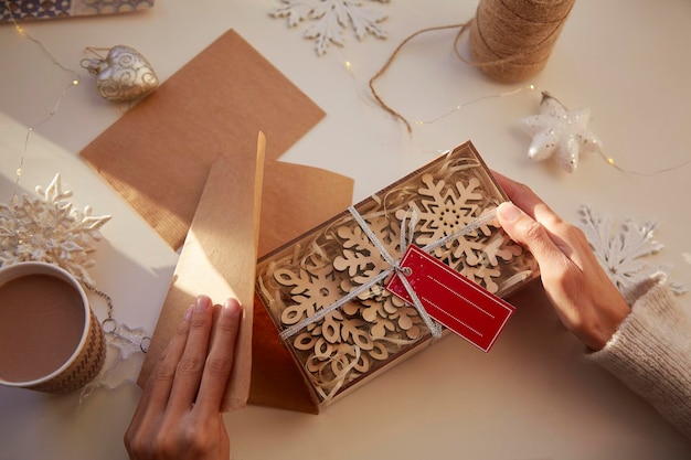 Mani femminili che avvolgono i regali di Natale a casa Casa accogliente Regali fatti a mano Preparativi natalizi