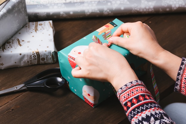 Mani femminili che avvolgono i regali di Natale sulla tavola di legno