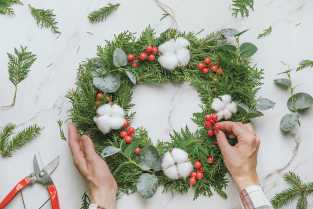 Mani femminili che decorano la ghirlanda di Natale fai da te