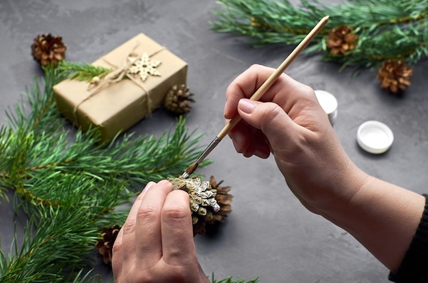 Mani femminili che dipingono le pigne per la decorazione di Natale