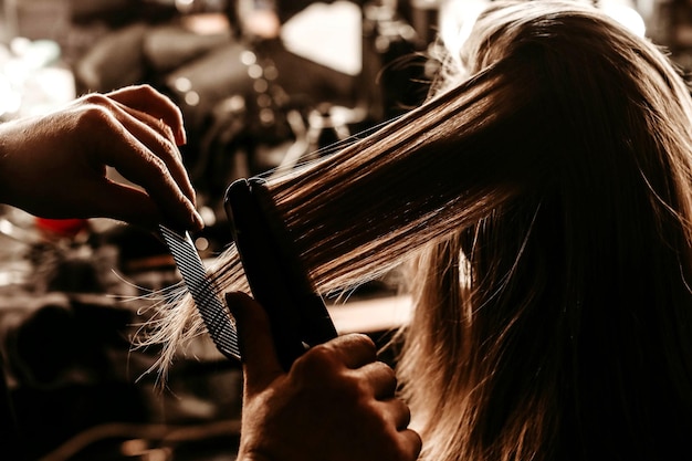 Mani femminili che disegnano i capelli di una giovane modella bionda nel backstage