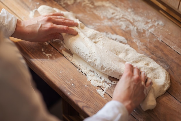 Mani femminili che formano l'impasto nella forma del pane Vista dall'alto delle mani di una donna che lavora con l'impasto il futuro pane