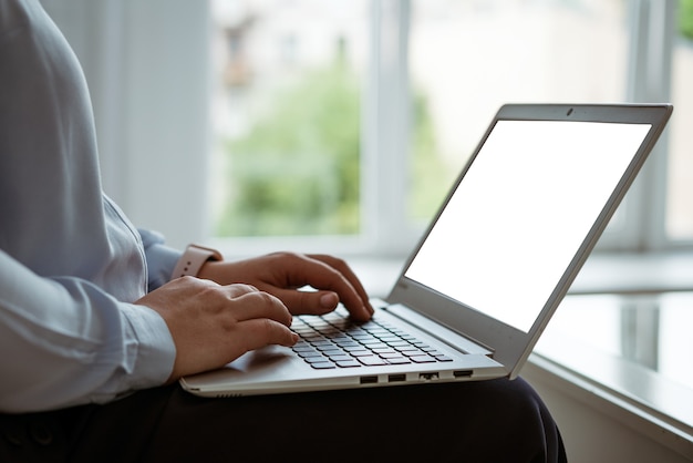 Mani femminili che lavorano dietro un laptop, senza volto