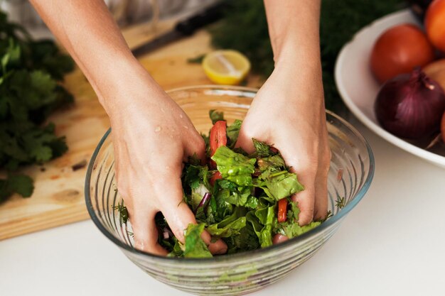 Mani femminili che mescolano insalata vegetariana nella ciotola