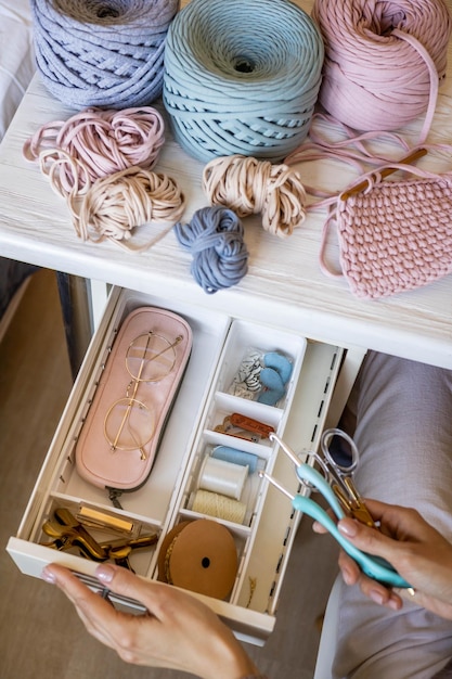 Mani femminili che mettono le forbici nel cassetto con accessori per cucire posizionando ordinatamente la vista dall'alto