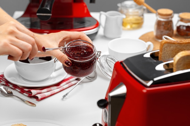 Mani femminili che preparano toast con marmellata di frutta