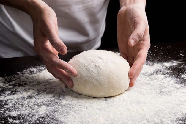 Mani femminili che producono pasta fresca sulla tavola di legno