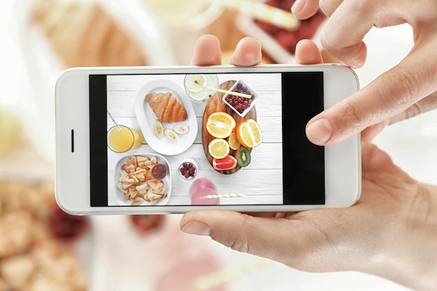 Mani femminili che scattano foto di una gustosa colazione sul tavolo