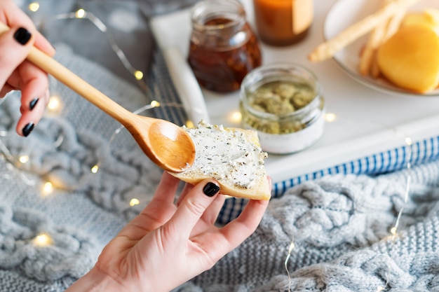 Mani femminili che spalmano la crema di formaggio sul pane fresco