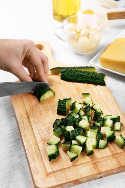 Mani femminili che tagliano le verdure per insalata in cucina